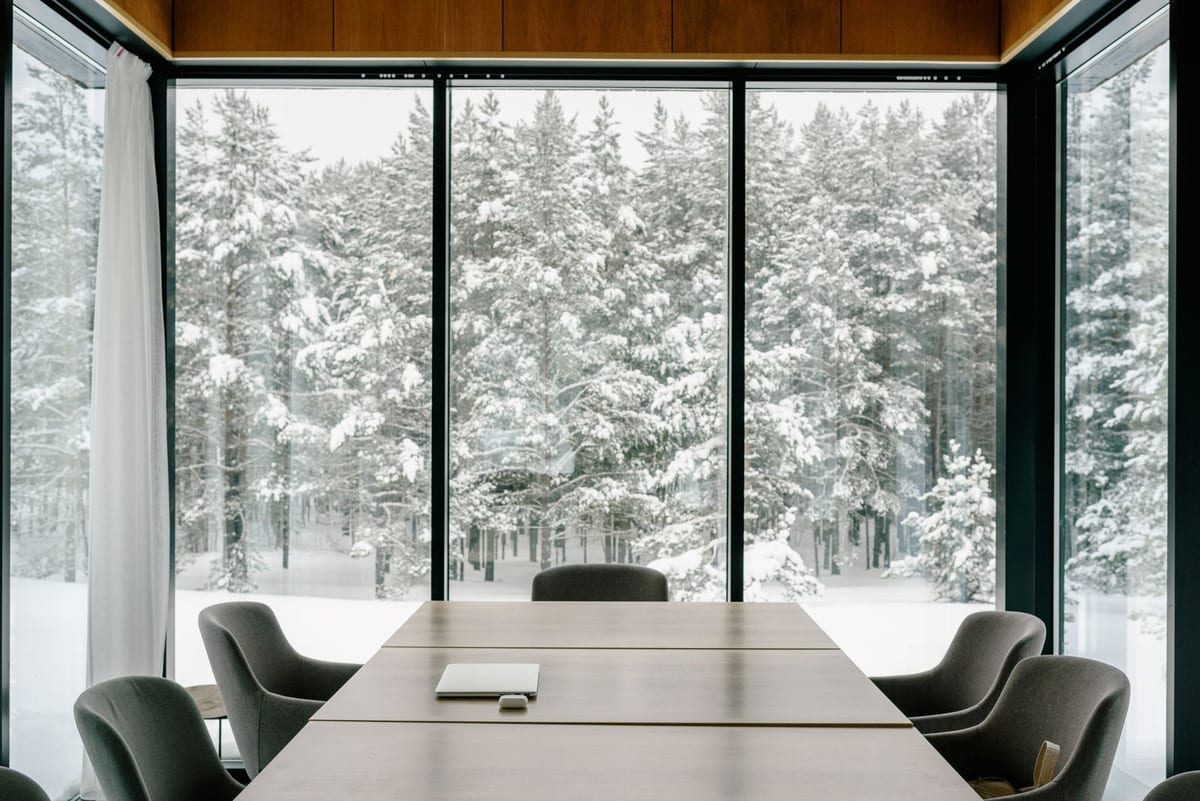 Moderne møterom med langbord og store vindusflater ut mot snødekt skog om vinteren