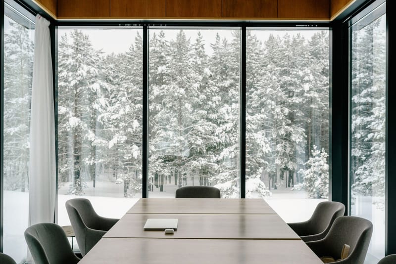 Moderne møterom med langbord og store vindusflater ut mot snødekt skog om vinteren